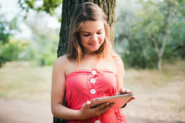 Giovane bella femmina caucasica utilizzando tablet nel parco — Foto Stock