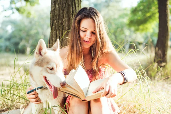 Молода красива біла жінка читає книгу в парку — стокове фото