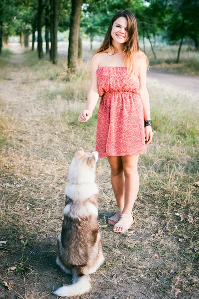 年轻美丽白种人女性培训与西伯利亚哈士奇犬小狗在公园里 — 图库照片