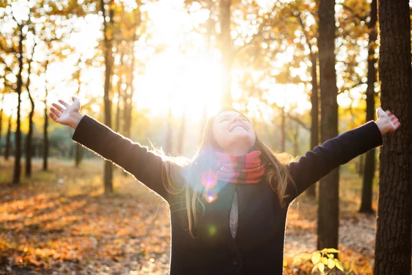 Joven mujer feliz con las manos animadoras en el parque. Mujer disfrutando del sol de otoño — Foto de Stock