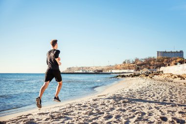 Çalışan adam. Erkek koşucu gündoğumu sırasında sahilde koşu