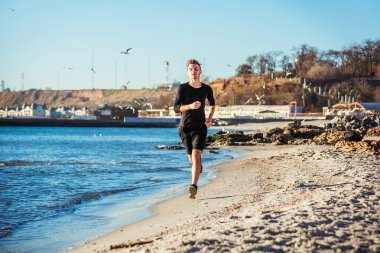 Çalışan adam. Erkek koşucu gündoğumu sırasında sahilde koşu