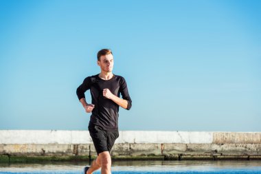 Çalışan adam. Erkek koşucu gündoğumu sırasında sahilde koşu
