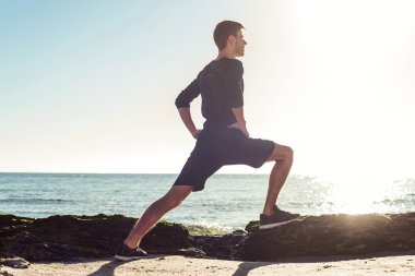 Kumsalda, sportif adam egzersizleri yapıyor çalışma dışarı genç erkek