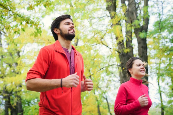 秋の公園、ジョギングを一緒にカップルで実行している若い白人カップル — ストック写真