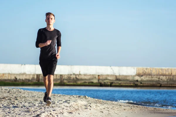 Běžící muž. Mužské běžec běhání během východu slunce na pláži — Stock fotografie