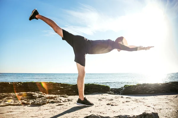 Junger Mann trainiert am Strand, sportlicher Mann macht Übungen — Stockfoto