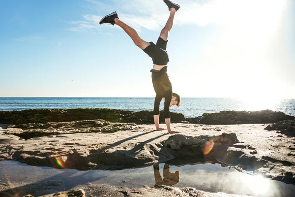 Junger Mann trainiert am Strand, sportlicher Mann macht Übungen — Stockfoto