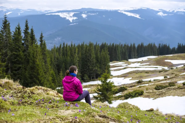 Νεαρή γυναίκα καυκάσιος κάθεται και απολαμβάνοντας τη θέα στα βουνά — Φωτογραφία Αρχείου