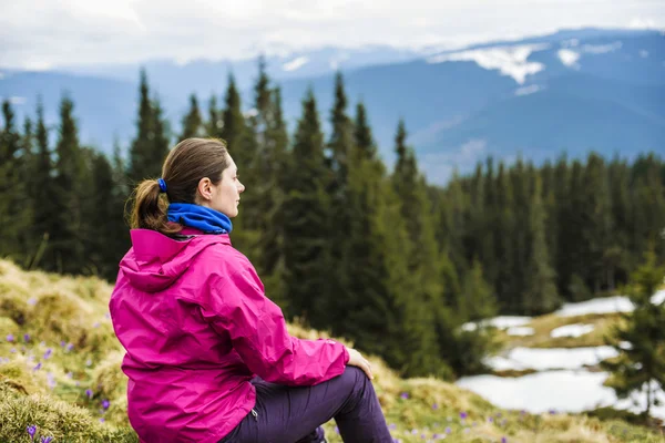 Junge kaukasische Frau sitzt und genießt die Aussicht in den Bergen — Stockfoto