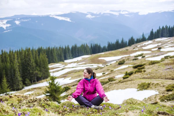 Junge kaukasische Frau sitzt und genießt die Aussicht in den Bergen — Stockfoto