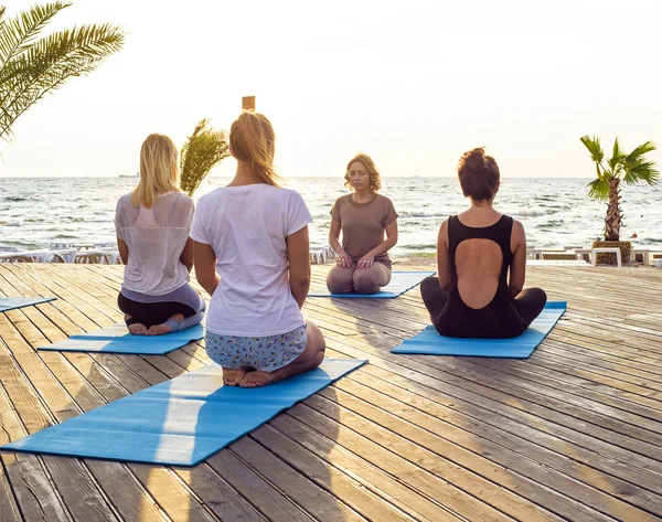 Grupa młodych samic praktykowania jogi na plaży podczas sunrise — Zdjęcie stockowe