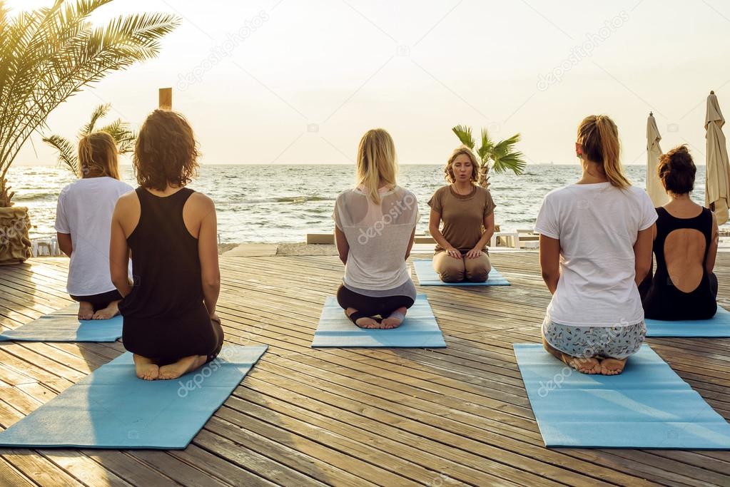 females practicing yoga on the seaside