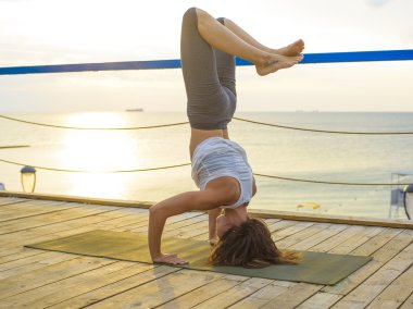 pratik Yoga sahilde gündoğumu sırasında genç beyaz kadın