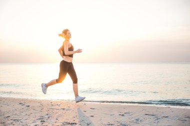 Çalışan kadın. Kadın atlet gündoğumu sırasında sahilde koşu.