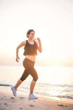 Çalışan kadın. Kadın atlet gündoğumu sırasında sahilde koşu.