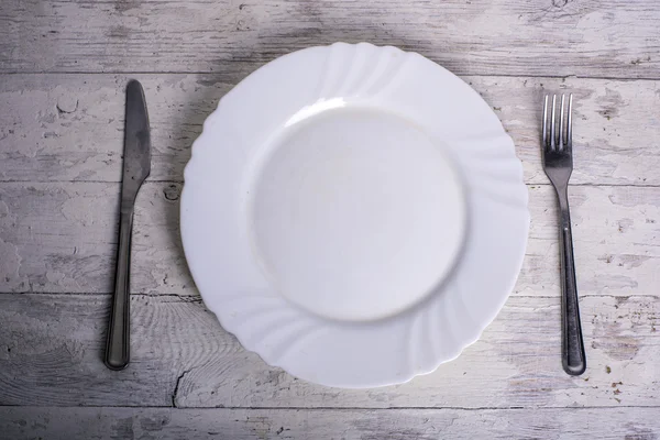 Assiette, couteau et fourchette sur fond blanc vintage en bois — Photo