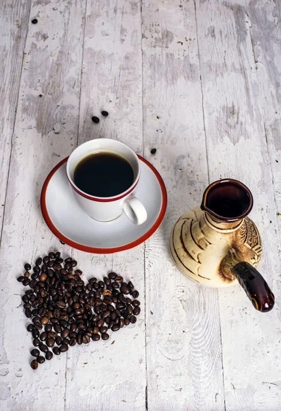 Kubek kawy i ziarna kawy na białym drewnianym tle — Zdjęcie stockowe