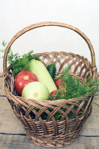 Čerstvá zelenina, okurky, squash, rajčata a fenyklu v proutěném koši na dřevěné pozadí — Stock fotografie