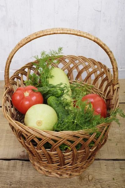 Légumes frais, concombres, courges, tomates et fenouil dans un panier en osier sur fond de bois — Photo