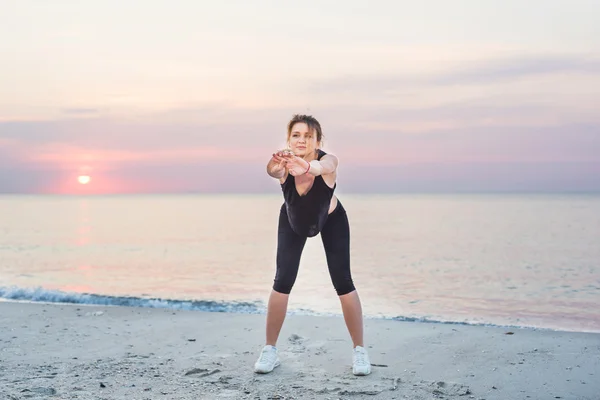 Modello di sport fitness sorridente felice facendo esercizi durante il lavoro all'aperto all'alba. Bella formazione femminile caucasica al di fuori sul mare al mattino — Foto Stock