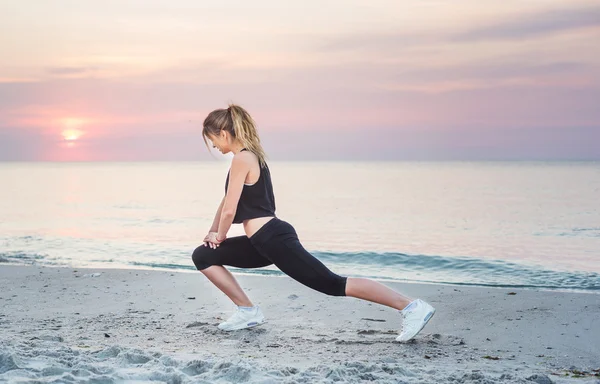 Model sport fitness uśmiechający się zadowolony robi ćwiczenia podczas zewnątrz wypracować na wschód. Piękny kaukaski kobiece szkolenia poza nad morzem rano — Zdjęcie stockowe