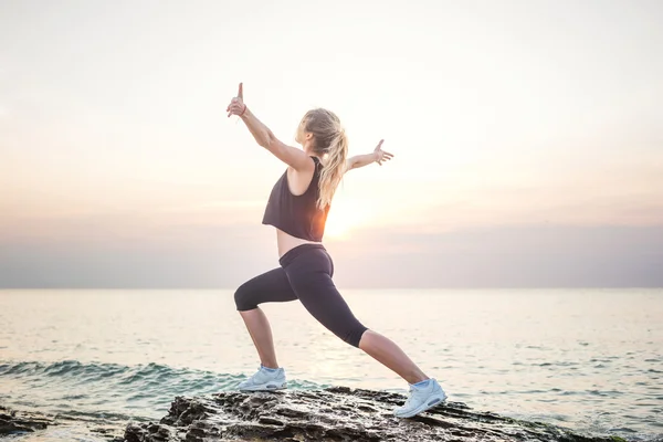 Fitness modelo deportivo sonriendo feliz haciendo ejercicios durante el ejercicio al aire libre a la salida del sol. Hermosa mujer caucásica entrenamiento al aire libre en la playa por la mañana —  Fotos de Stock