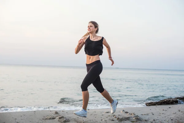 Une femme qui court. Coureuse jogging pendant le lever du soleil sur la plage . — Photo