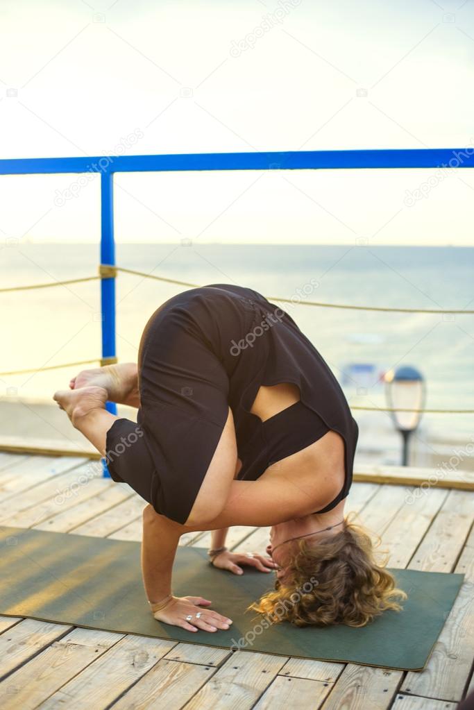 young caucasian female practicing yoga on the seaside during the sunrise