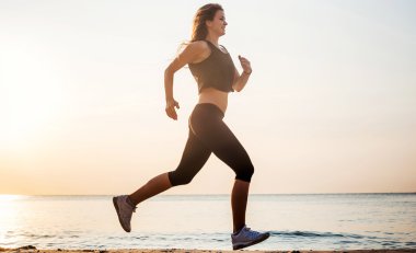 Çalışan kadın. Kadın atlet gündoğumu sırasında sahilde koşu.