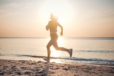 Çalışan kadın. Kadın atlet gündoğumu sırasında sahilde koşu.