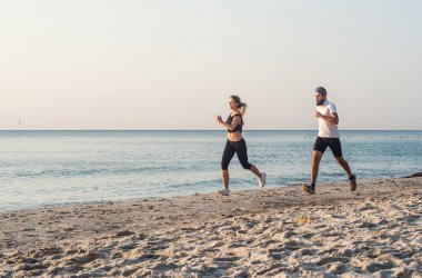 Kişi - kadın ve erkek atlet koşucular sahilde koşu çalışmıyor. Sağlıklı yaşam tarzı açık havada gündoğumu veya günbatımı sırasında egzersiz genç fitness çift uygun
