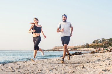 Kişi - kadın ve erkek atlet koşucular sahilde koşu çalışmıyor. Sağlıklı yaşam tarzı açık havada gündoğumu veya günbatımı sırasında egzersiz genç fitness çift uygun
