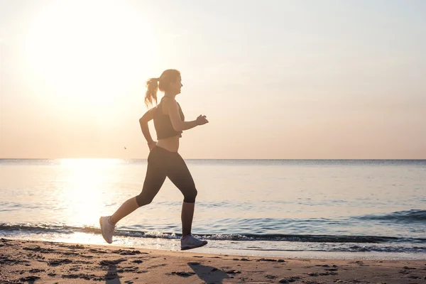 Çalışan kadın. Kadın atlet gündoğumu sırasında sahilde koşu. — Stok fotoğraf