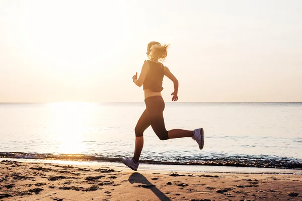 Çalışan kadın. Kadın atlet gündoğumu sırasında sahilde koşu. — Stok fotoğraf