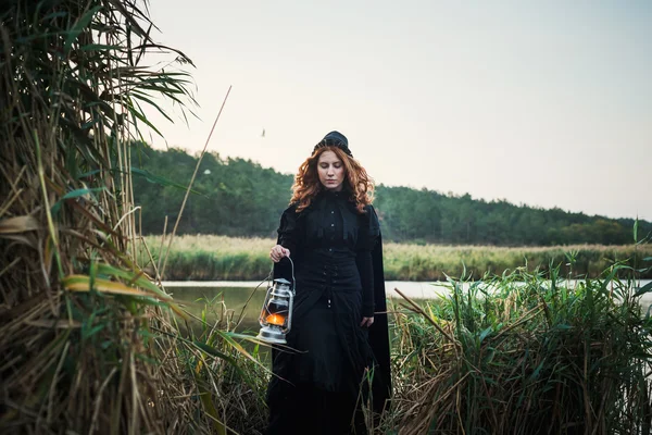 Witch with light on a swamp. Witch practicing magic on a swamp. Halloween concept — Stock Photo, Image