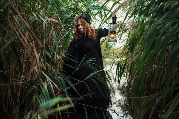 Bruja con luz en un pantano. Bruja practicando magia en un pantano. Concepto Halloween — Foto de Stock