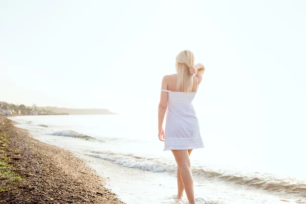 Genç güzel beyaz kadın gündoğumu veya günbatımı sırasında plajda güneşin tadını — Stok fotoğraf