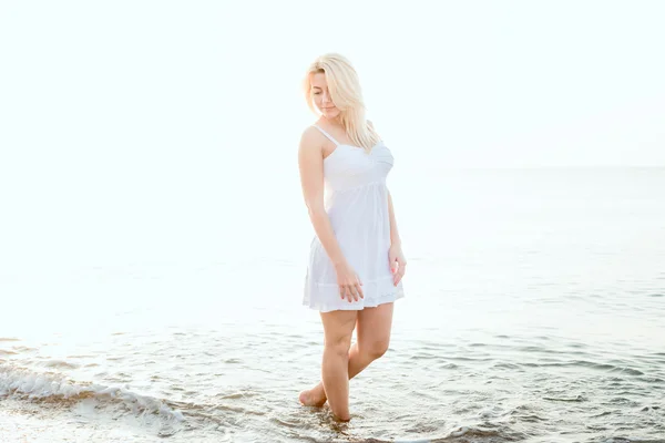 Young beautiful caucasian female enjoying the sun on beach during sunrise or sunset — Stock Photo, Image