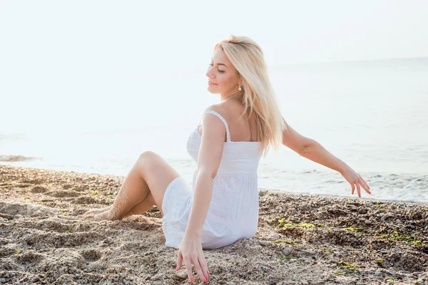 Jovem bela mulher caucasiana desfrutando do sol na praia durante o nascer do sol ou pôr do sol — Fotografia de Stock