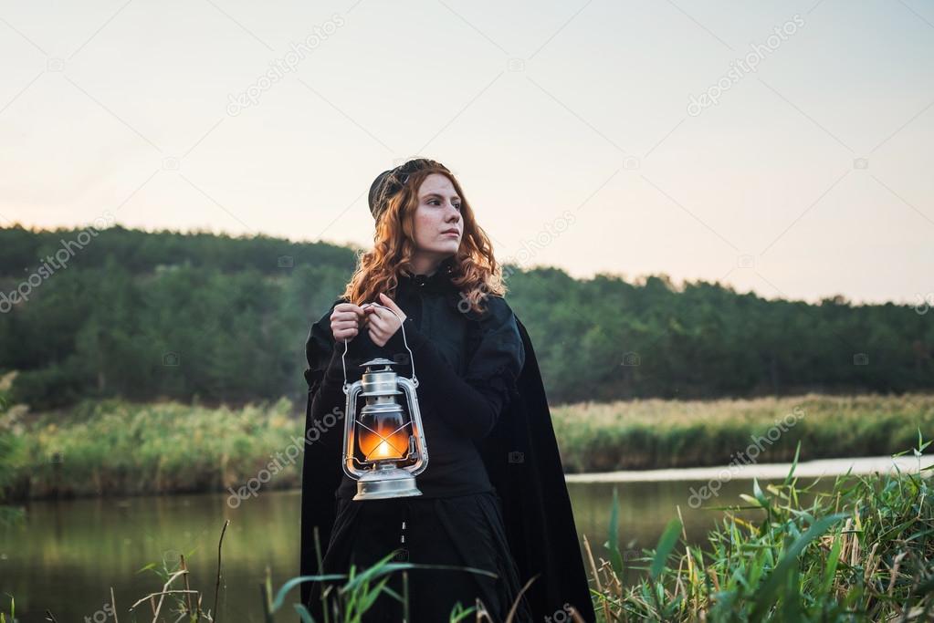 witch with light on a swamp. Witch practicing magic on a swamp. Halloween concept