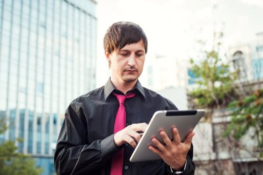 Açık havada tablet kullanan bir iş adamı.