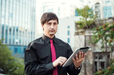 Açık havada tablet kullanan bir iş adamı.