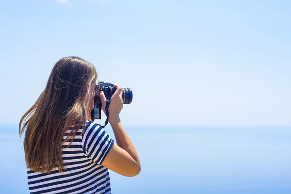 Young caucasian female with camera on a cliff, woman taking photos on seaside — Stock Photo, Image