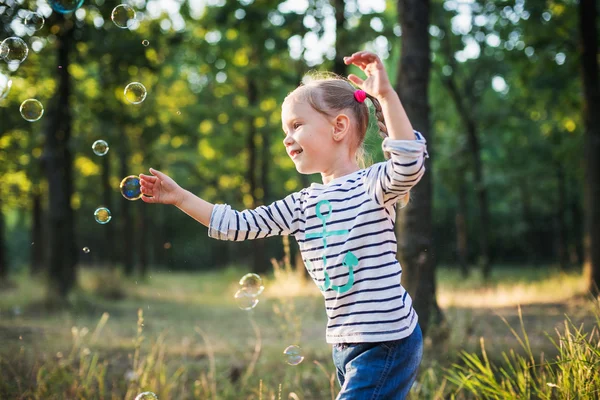 Liten flicka spelar med bubbla fläkt i parken — Stockfoto