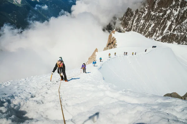 Alpine ascent on Aiguille du Midi mountain in french alps, chamonix. Group of people climbing the mountain, making extreme ascent, going through difficulties