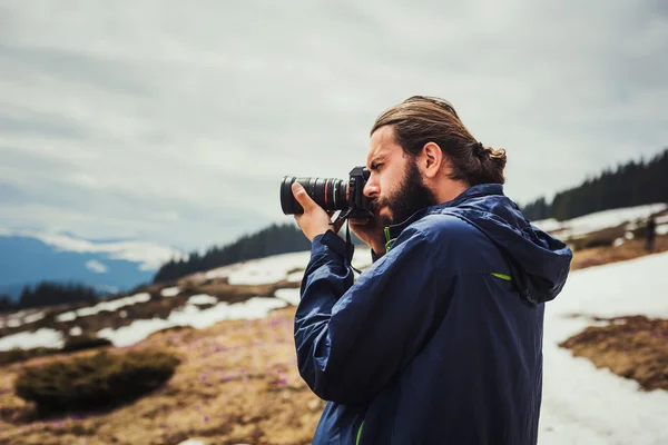 Macho com câmera tirando fotos nas montanhas — Fotografia de Stock