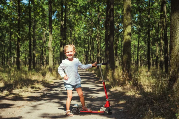 Küçük kız sürme scooter Park — Stok fotoğraf
