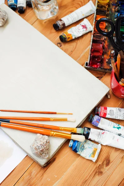 Akwarela farby, farby olejne, telefon, okulary i szczotki na stole w studio artystyczne. — Zdjęcie stockowe