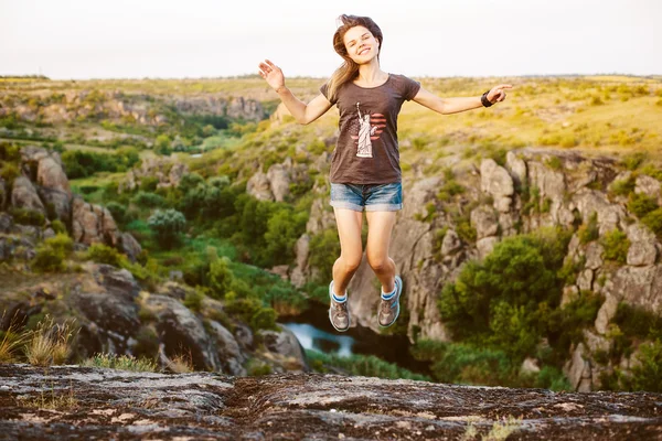 Jovem caucasiano fêmea saltando no cânion, menina se divertindo na bela paisagem natural com rochas — Fotografia de Stock